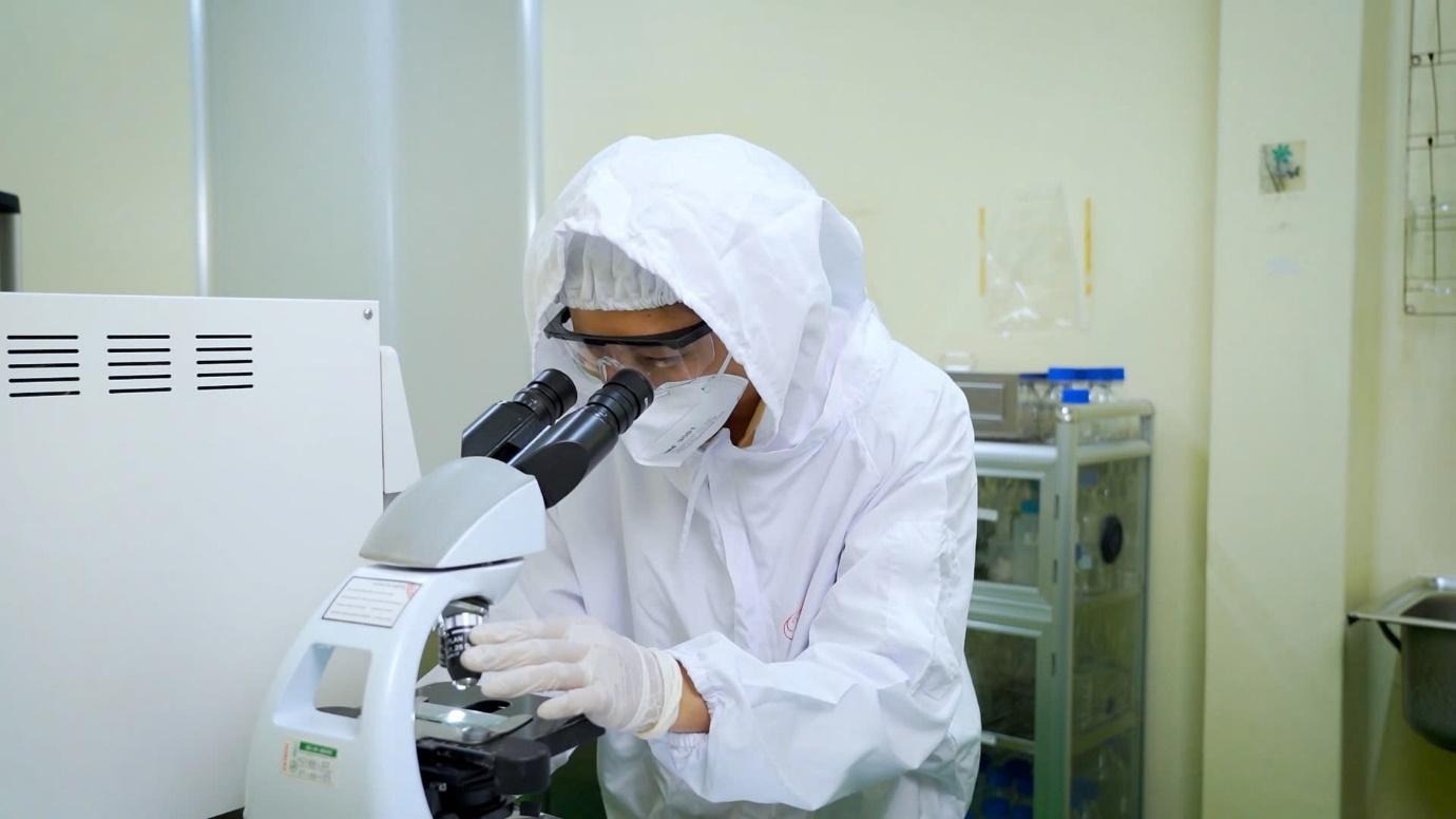 A person in a white suit looking through a microscopeAI-generated content may be incorrect.